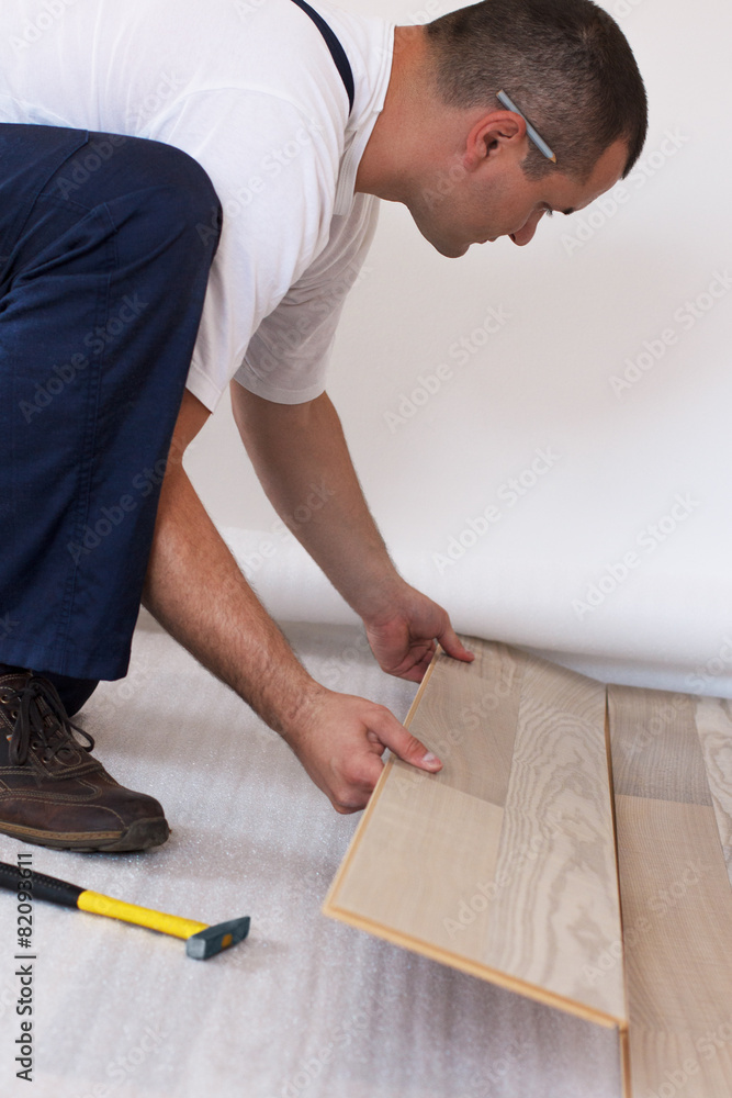 Man laying laminate flooring in a home. Man laying laminate flooring in a home.