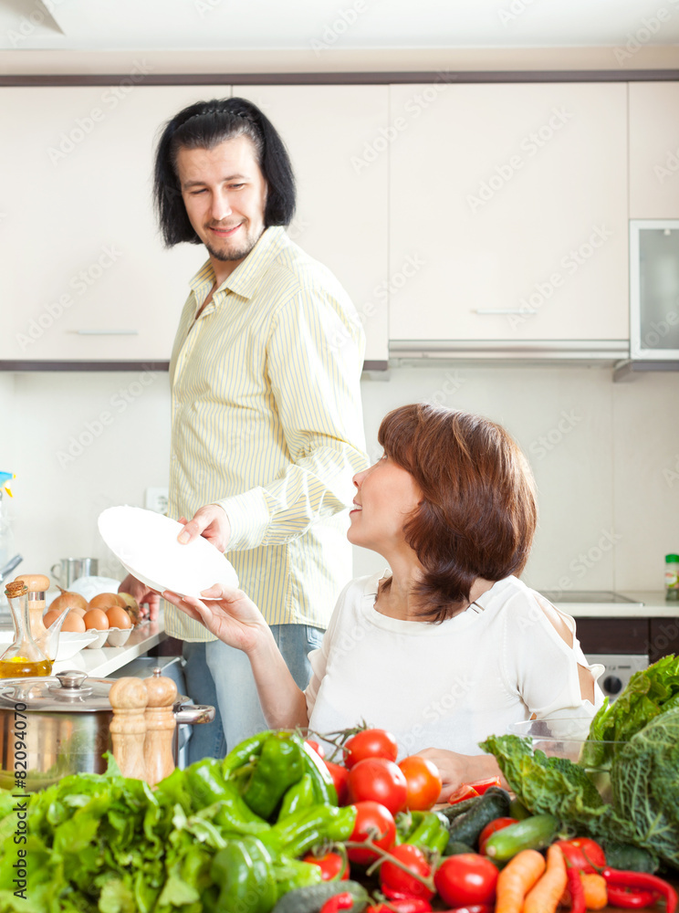 Man and woman with vegetables in kitchen