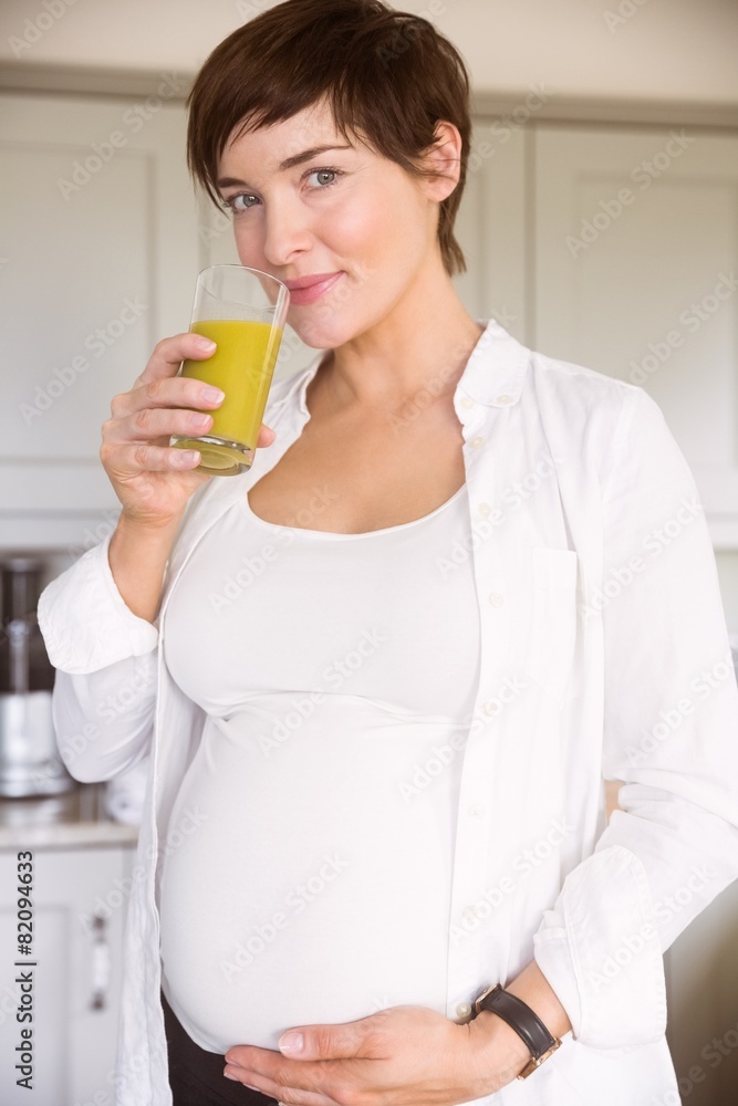 Pregnant woman drinking glass of orange juice Pregnant woman drinking glass of orange juice