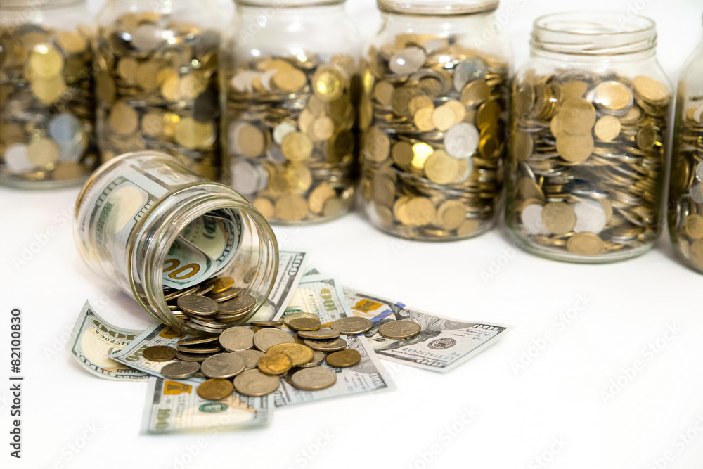 Horizontal shot of coins spilling from coin jar Horizontal shot of coins spilling from coin jar
