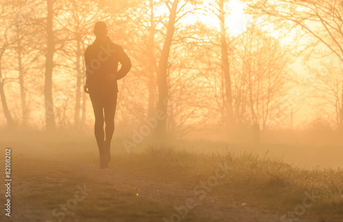 Silhouette of a runner during a foggy sunrise.