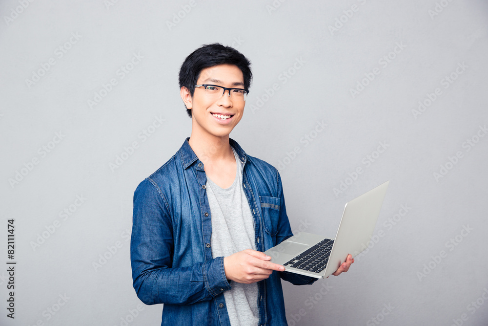 Smiling asian man standing with laptop Smiling asian man standing with laptop