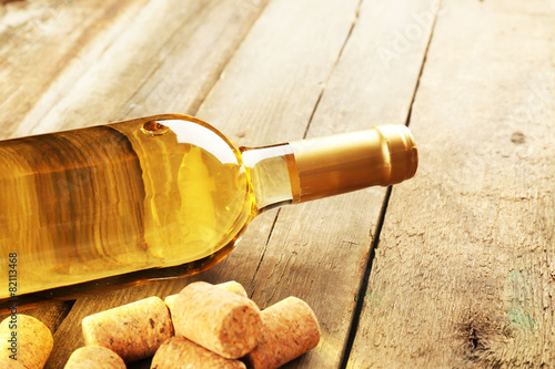 Glass bottle of wine with corks on wooden table background