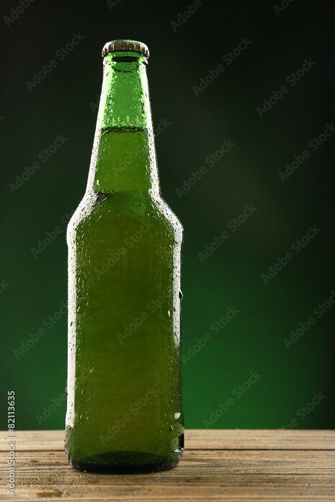 Glass bottle of beer on dark green background Glass bottle of beer on dark green background