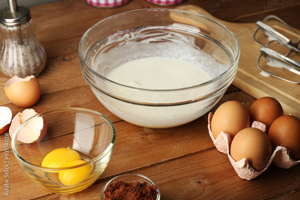 Preparation cream with eggs in glass bowl on wooden background Preparation cream with eggs in glass bowl on wooden background