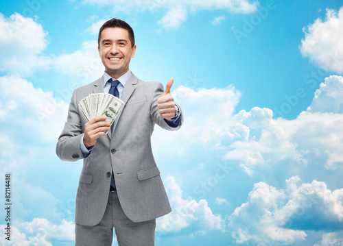smiling businessman with money showing thumbs up © Syda Productions