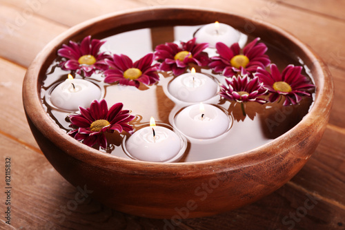 Bowl of spa water with flowers and candles