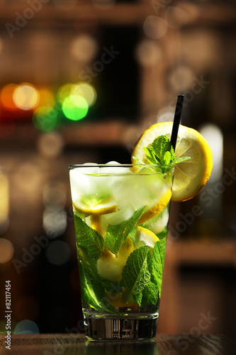 Glass of cocktail in bar on bright blurred background