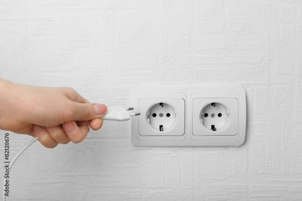 Hand putting plug in electricity socket close up Hand putting plug in electricity socket close up