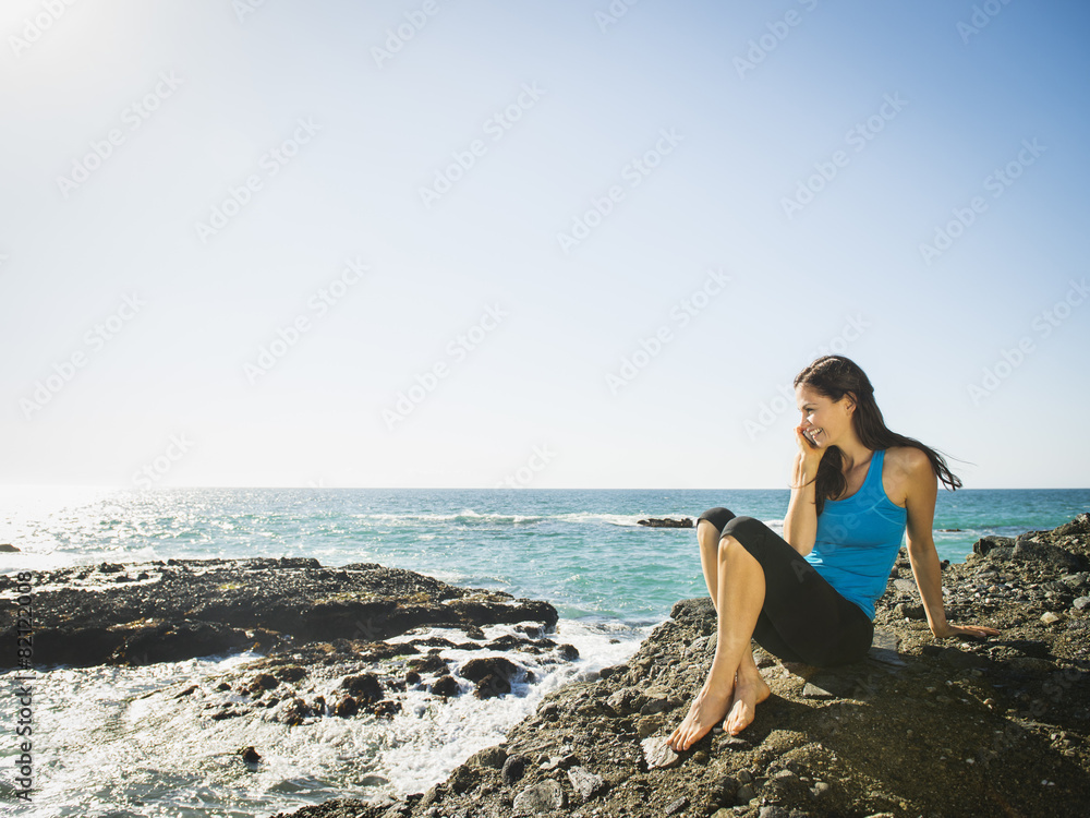 Mixed race woman smiling on rocky beach Mixed race woman smiling on rocky beach