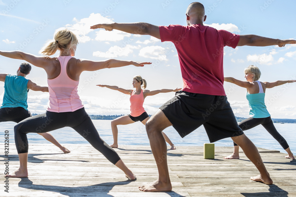 Caucasian people practicing yoga on wooden dock Caucasian people practicing yoga on wooden dock