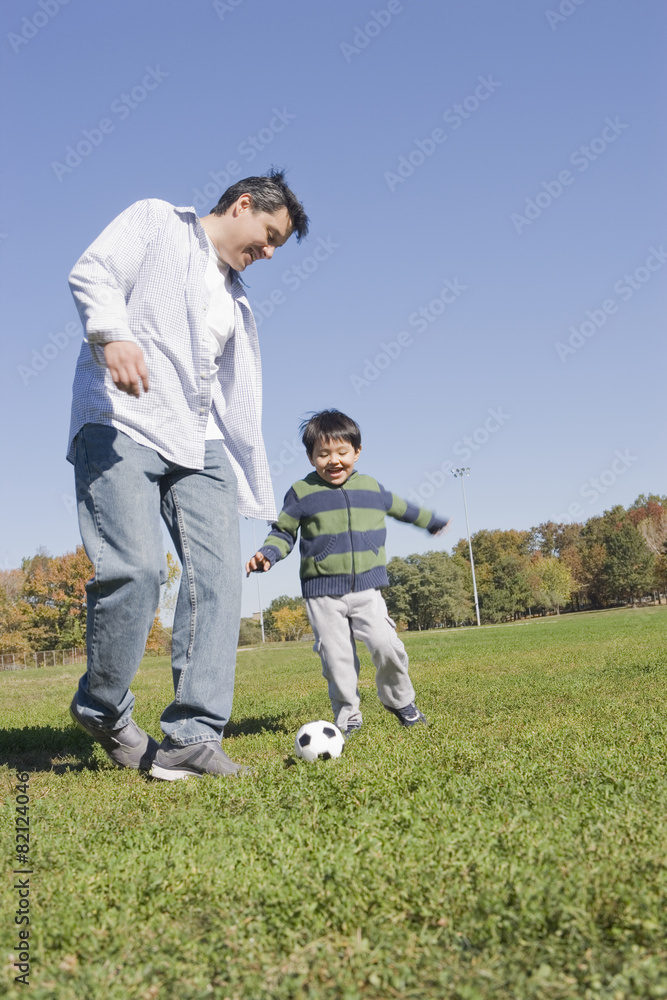 Hispanic father and son playing soccer outdoors Hispanic father and son playing soccer outdoors