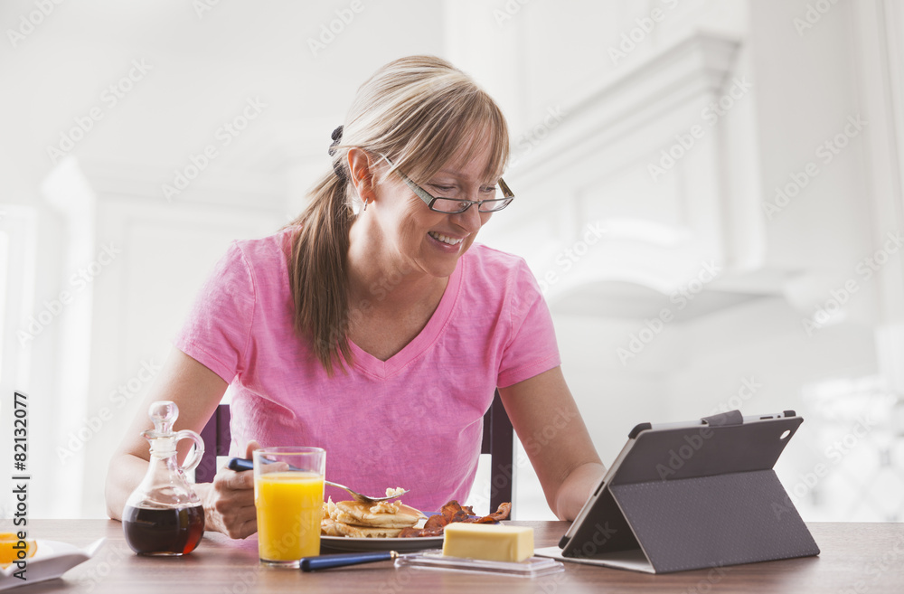 Caucasian woman using tablet computer at breakfast Caucasian woman using tablet computer at breakfast