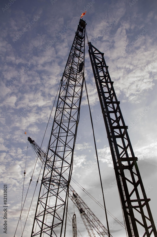 Cranes Silhouette Against Sky With Clouds Cranes Silhouette Against Sky With Clouds