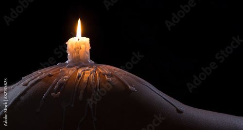 Body scape of a well-shaped woman with burning candle and wax on photo