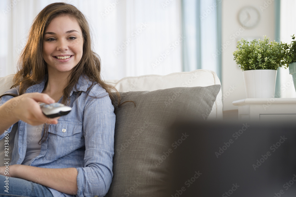 Hispanic girl watching television on sofa Hispanic girl watching television on sofa