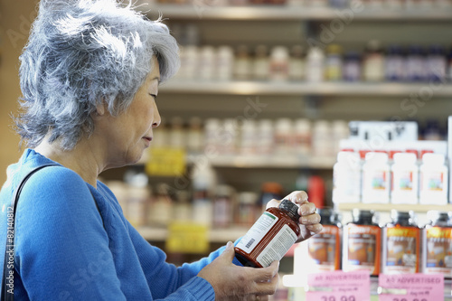 Senior Asian woman reading vitamin label photo