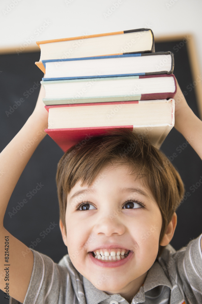 Hispanic boy balancing books on head Hispanic boy balancing books on head