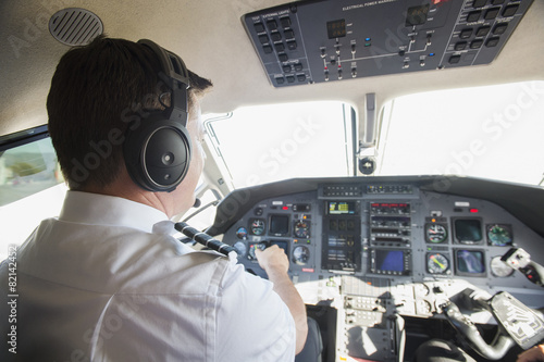 Caucasian pilot working in airplane cockpit photo