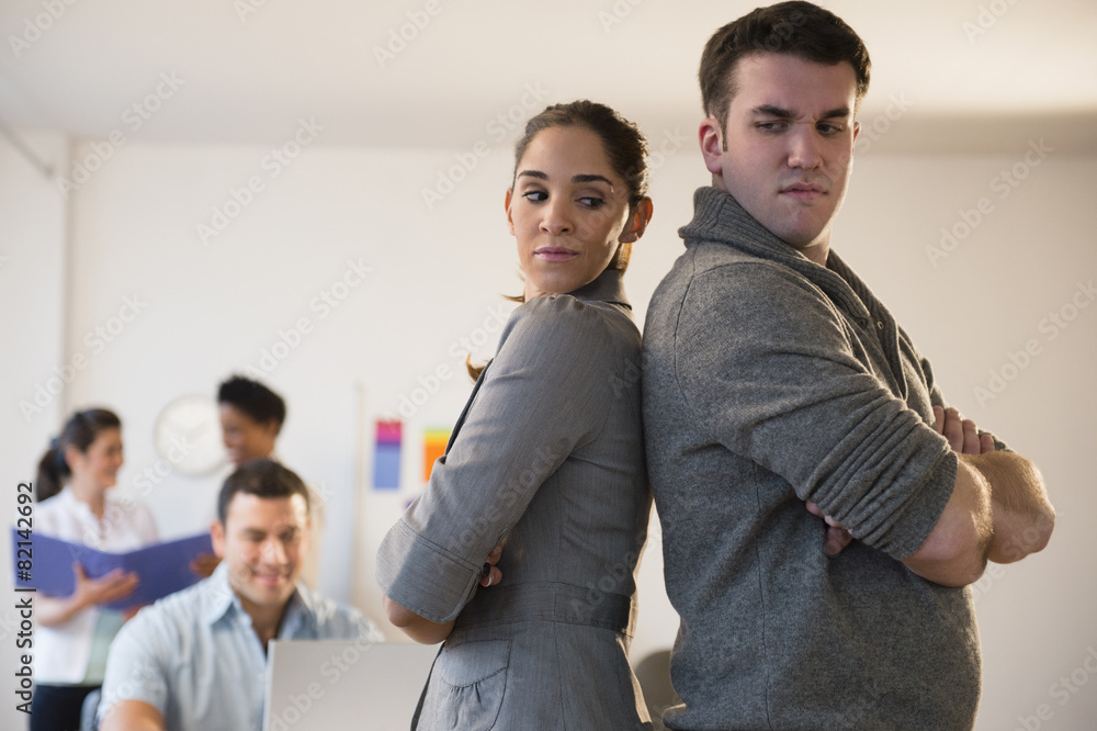 Business people standing back to back in office Business people standing back to back in office