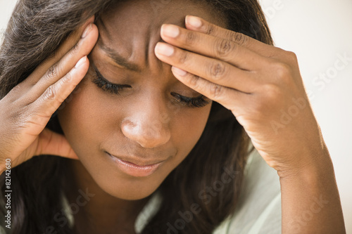 Black woman frowning with head in hands photo