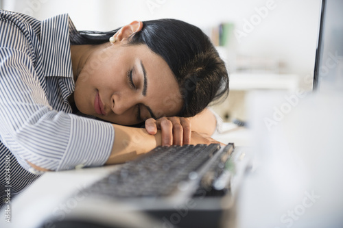 Indian businesswoman sleeping on desk in office photo