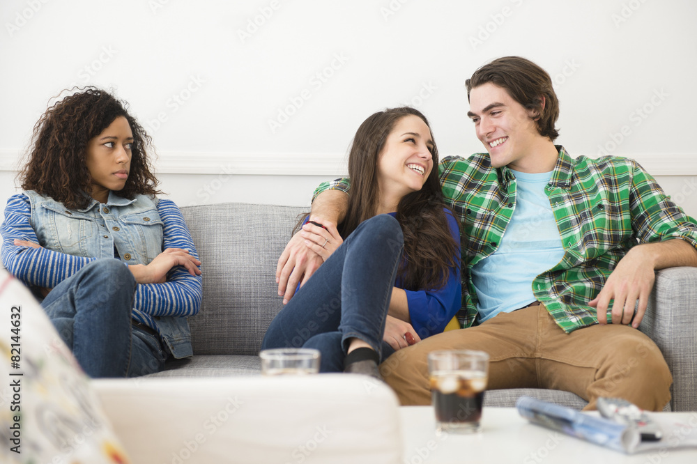 Couple ignoring friend on sofa Couple ignoring friend on sofa
