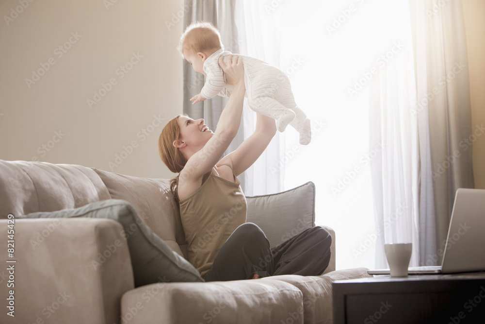 Caucasian mother on sofa lifting son Caucasian mother on sofa lifting son