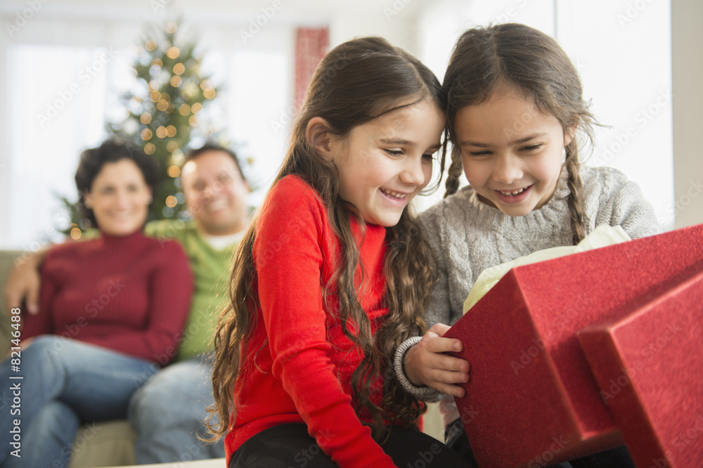 Smiling girls opening Christmas present Smiling girls opening Christmas present