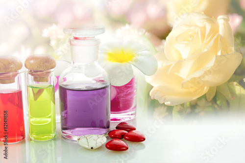 Bottles of natural aroma oil on flowers background