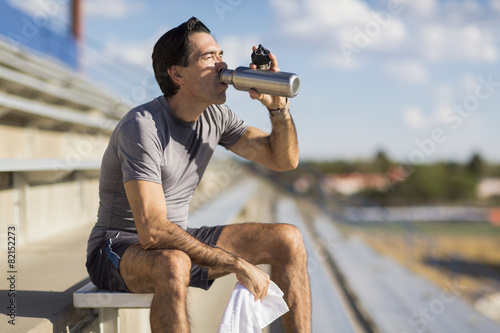 Hispanic athlete resting on bleachers photo