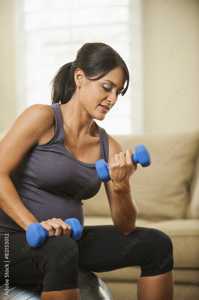 Pregnant Hispanic woman lifting weights Pregnant Hispanic woman lifting weights