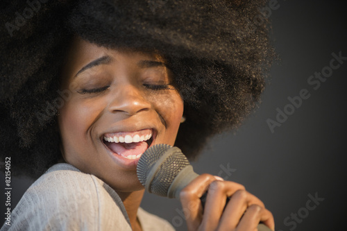Mixed race woman singing into microphone
