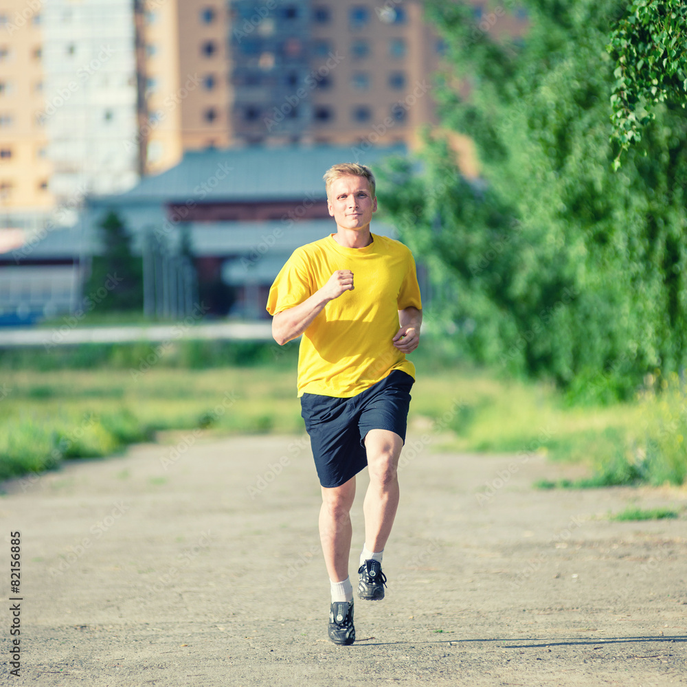 Sporty man jogging in city street park. Outdoor fitness. Sporty man jogging in city street park. Outdoor fitness.