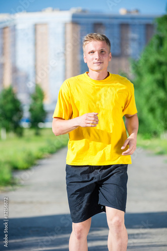 Sporty man jogging in city street park. Outdoor fitness. © mr.markin