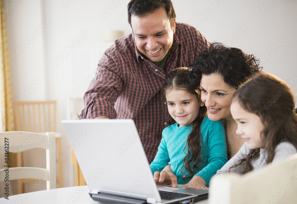 Family using laptop together at table Family using laptop together at table