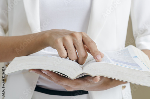 closeup of woman’s hands skimming through a dictionary photo