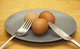 real plain easter eggs on plate with knife and fork