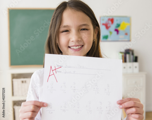 Mixed race girl holding paper with A+ grade