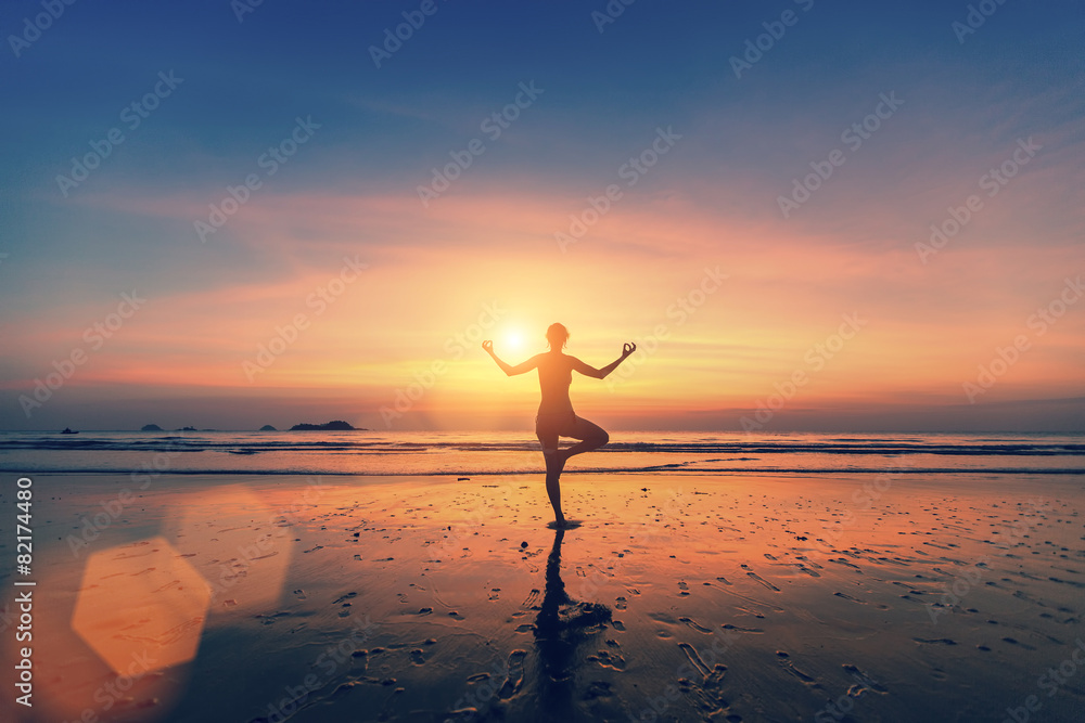 Silhouette of woman meditating on the sea beach. Yoga.