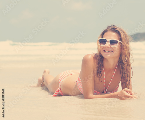 beautiful young woman lying on the beach against the sea