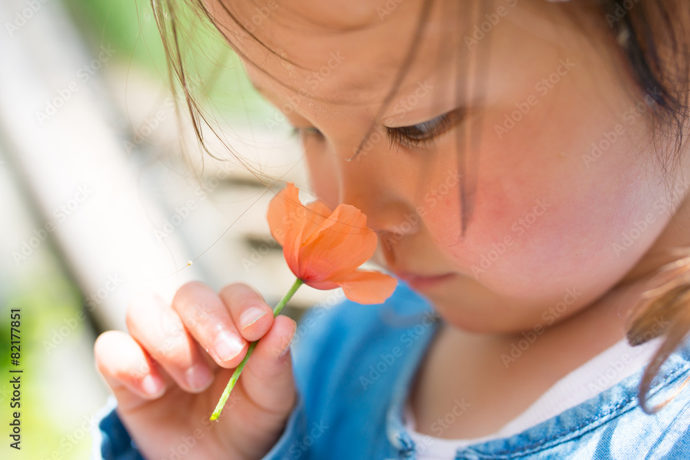 オレンジ色の花の香りを嗅ぐ女の子