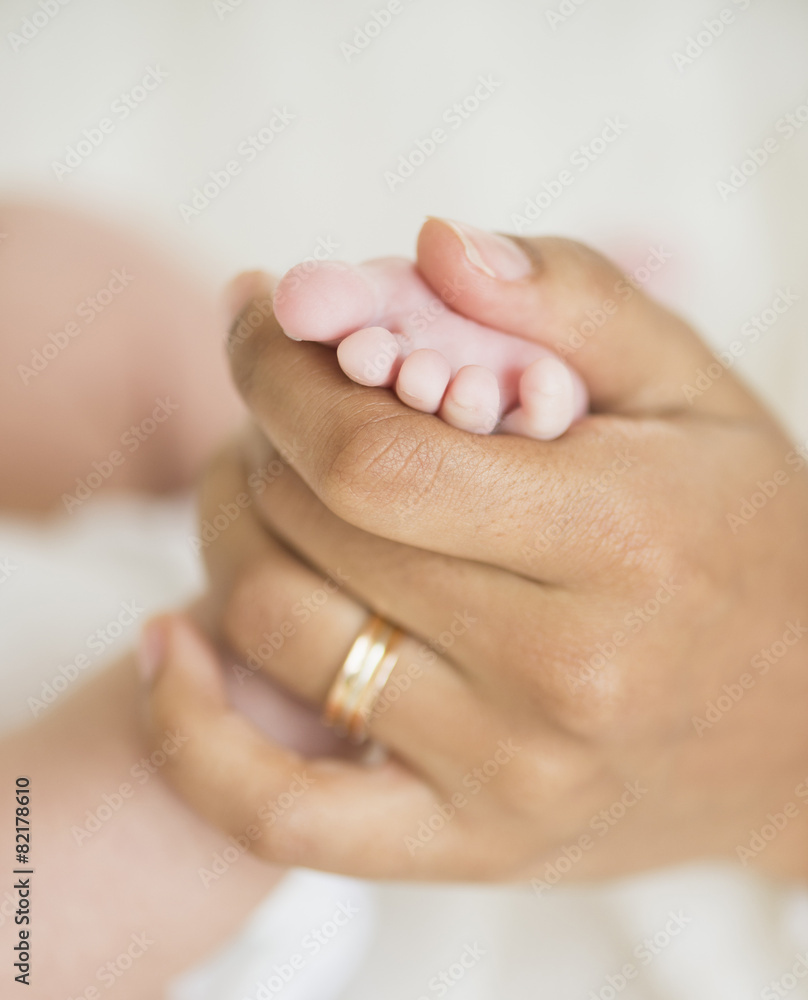 Hispanic mother holding infant's foot Hispanic mother holding infant's foot