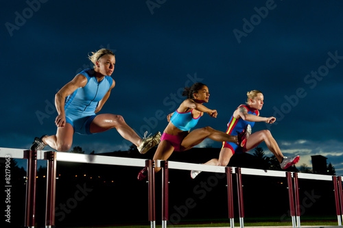 Runners jumping hurdles in race photo