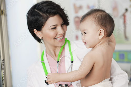 Doctor holding smiling baby in doctor's office photo