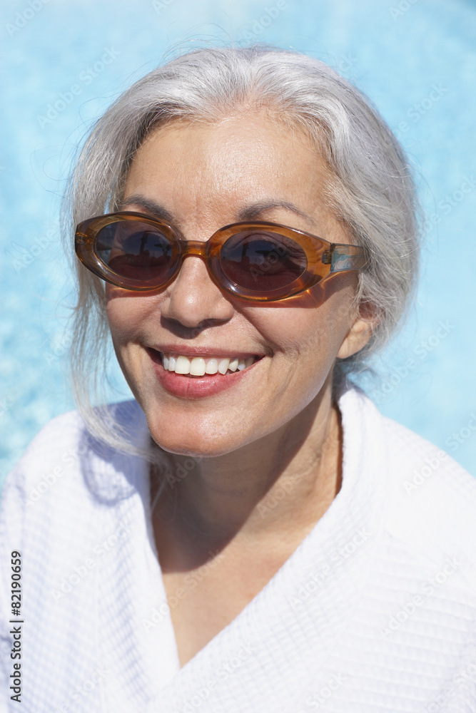 Woman at poolside in bathrobe and sunglasses Woman at poolside in bathrobe and sunglasses