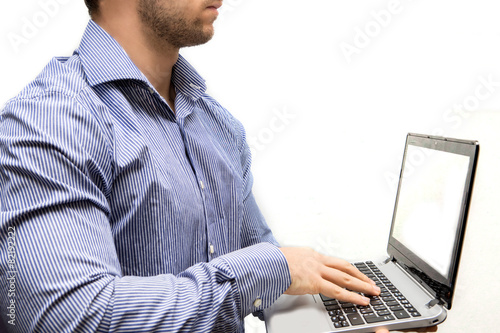 man in shirt with in hand a laptop and he writes