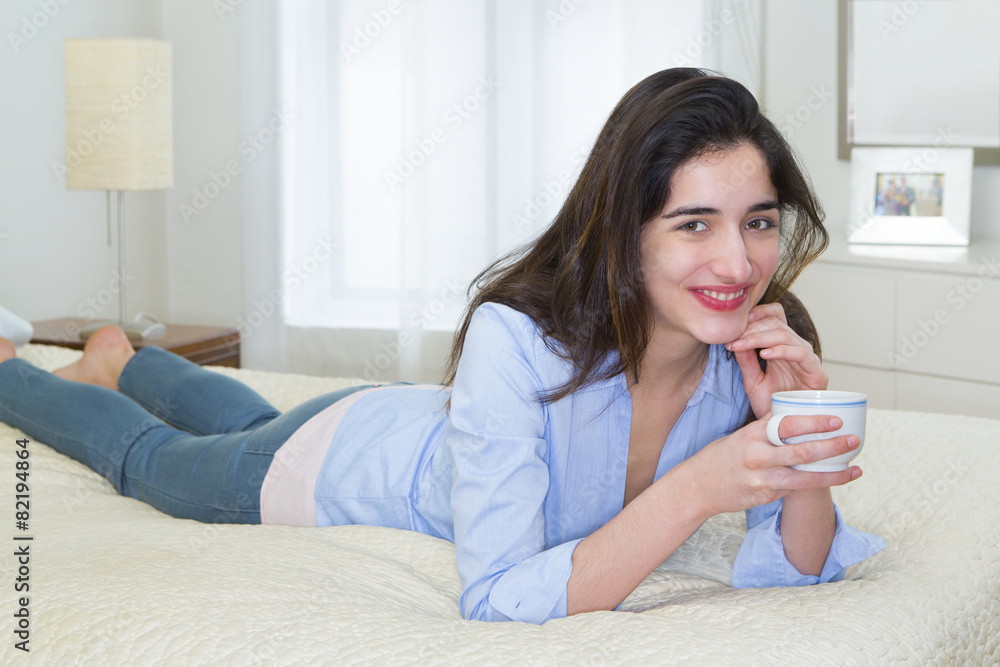 Hispanic woman enjoying cup of coffee on bed Hispanic woman enjoying cup of coffee on bed