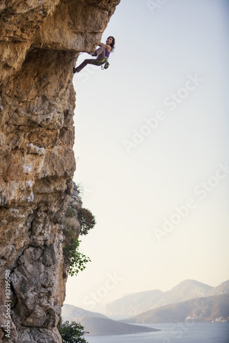 Female rock climber on cliff against view of islands
