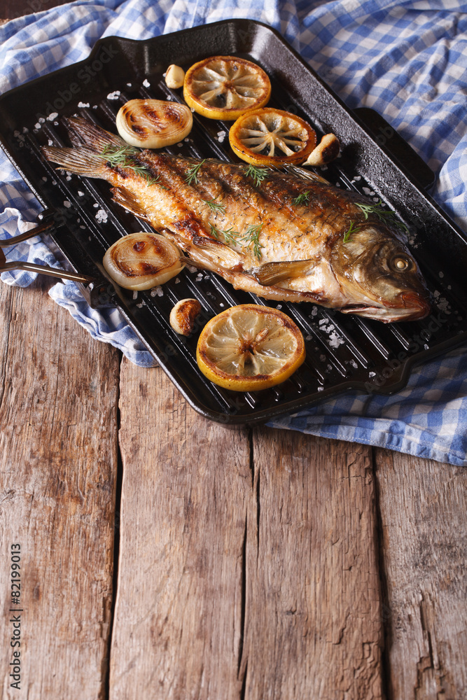 fried carp with lemon, onion and spices on the grill pan